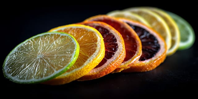 Row of colorful fresh citrus slices on a black background