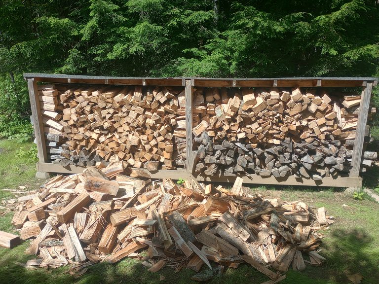 Split firewood stacked in bins with loose firewood in front