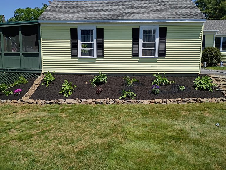 Refreshed garden bed with new mulch, plantings, and a clean stone edge