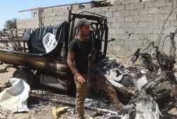 A member from Iraqi security forces stands next to a wreckage of a vehicle belonging to Islamic state militants during a military operation to fight against Islamic State militants in the town of Hit in Anbar province, April 2, 2016. REUTERS/Stringer