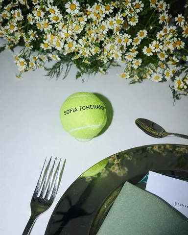 Guests gathered for dinner set on the court, where table details reflected the c