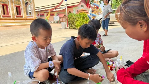 หลังจากที่ลูกๆไปเก็บเหรียญโปรยทานมา ก็มานั่งแกะเหรียญและพากันลุ้นว่าจะได้เหรียญอ