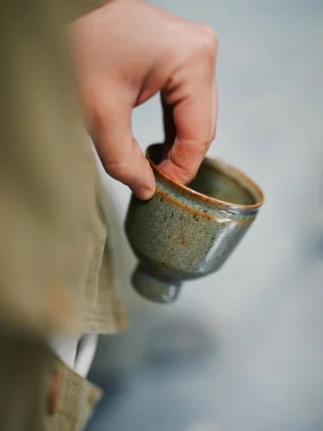 A small cup with a very metallic lip, a byproduct of the piece being twice fired