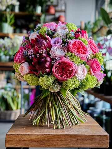 Vibrant garden roses, playful wax flowers, and lime green viburnum come together