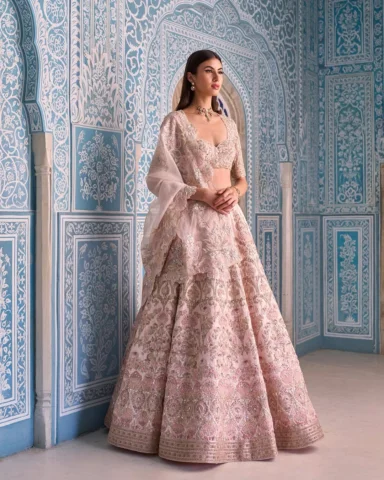 A soft blush-pink hand-embroidered bridal lehenga crafted with delicate lotus mo