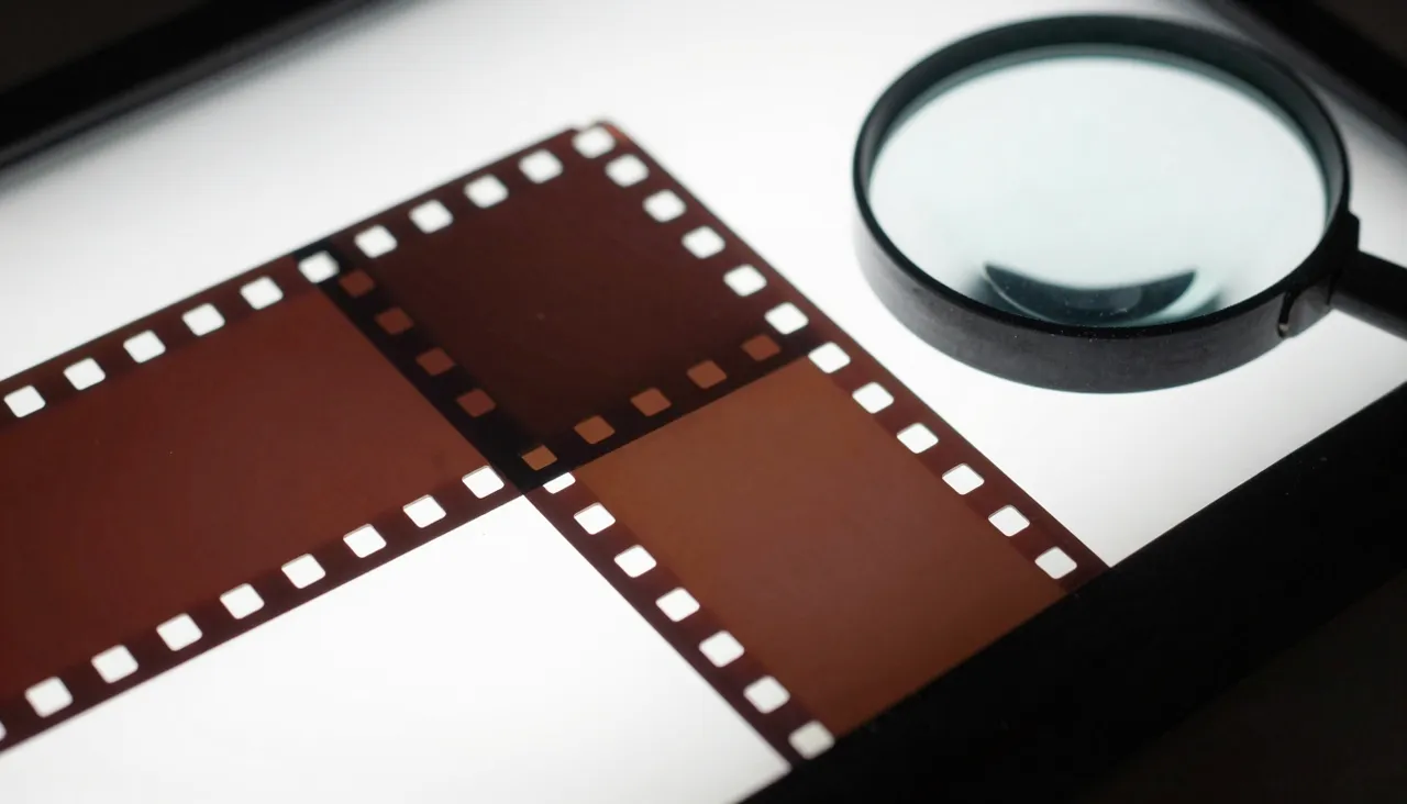 Macro shot of an old film strip beside a magnifying glass