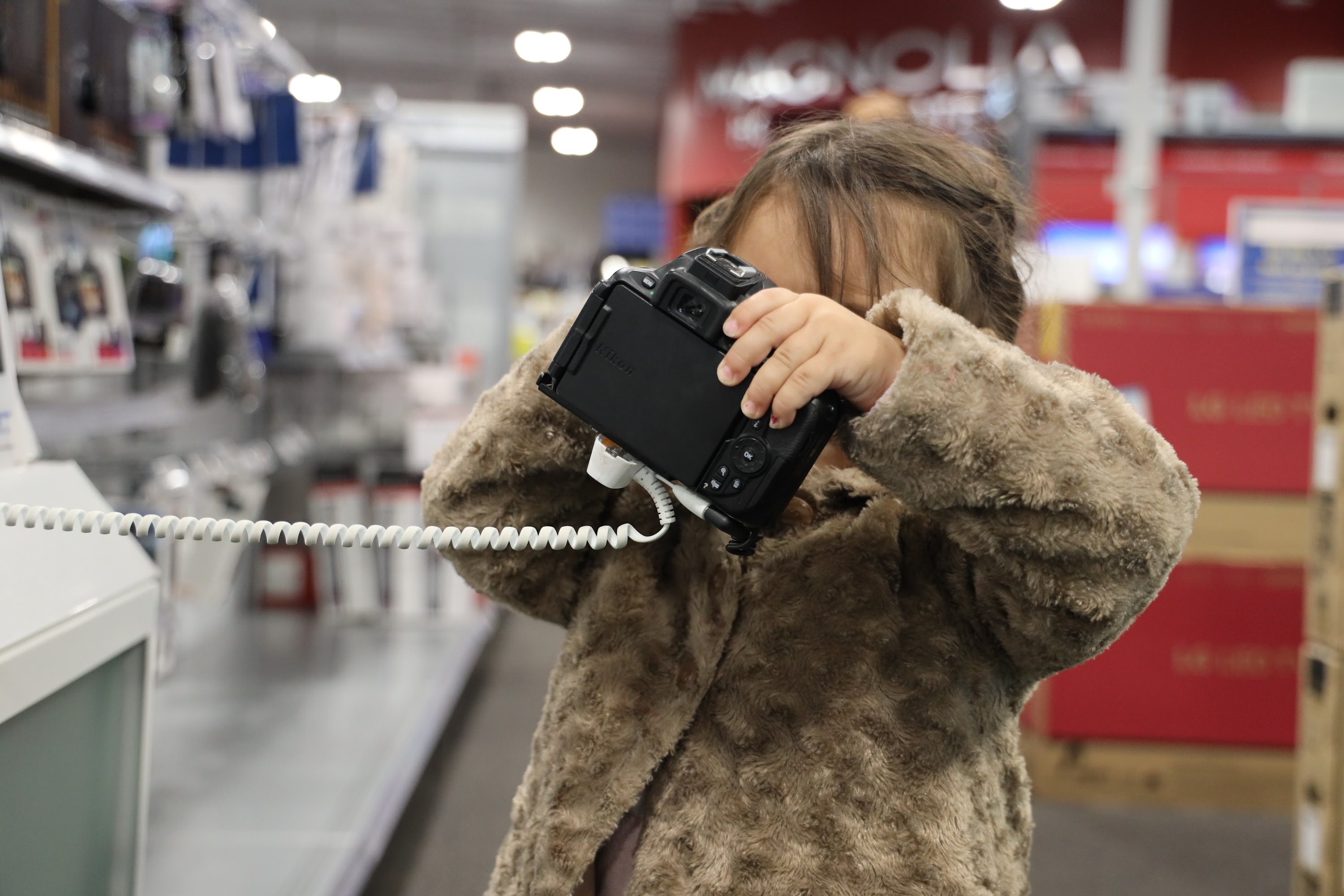 Child Holding Camera in Store