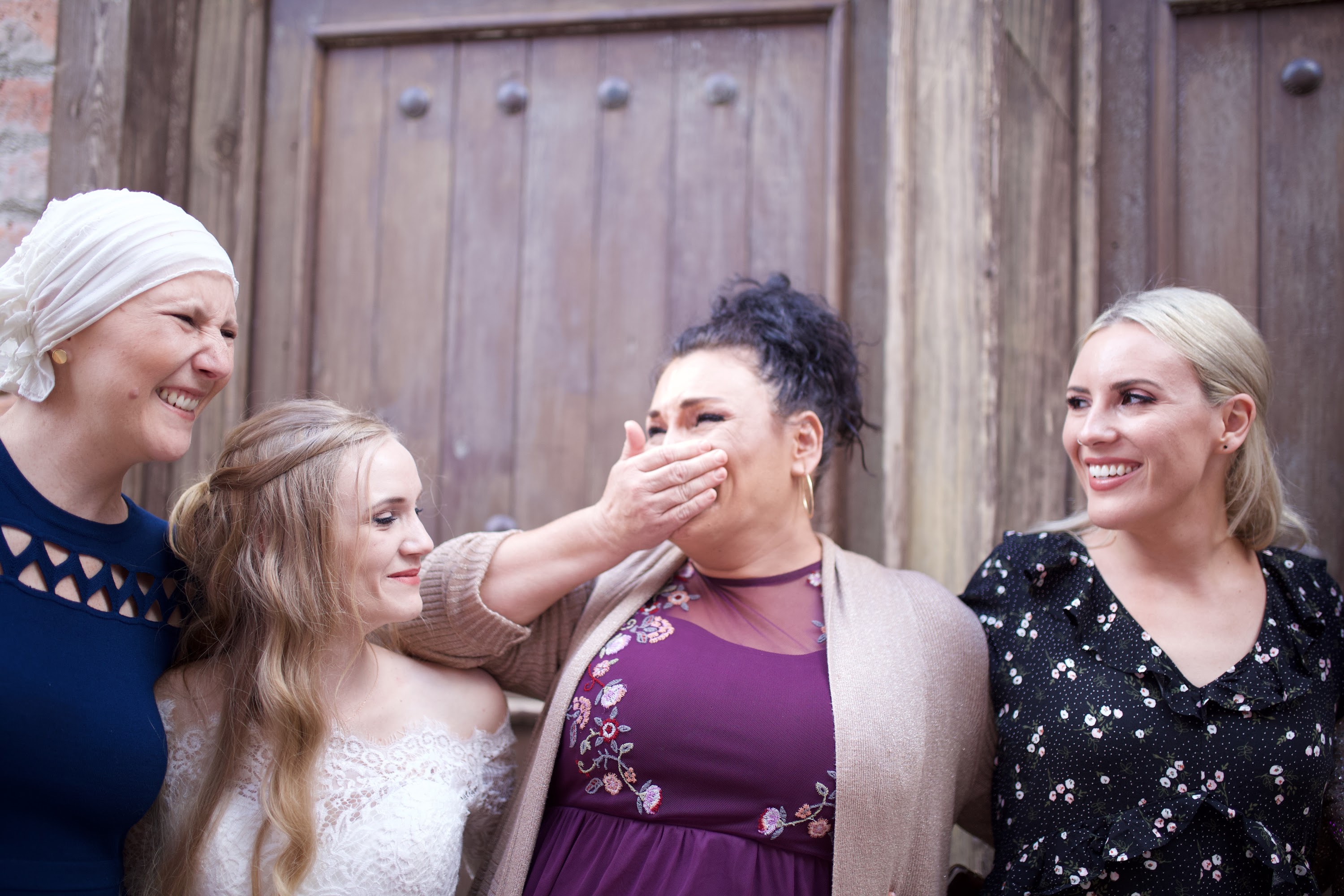 Four Women Sharing a Joyful Moment Outside a Wooden Door