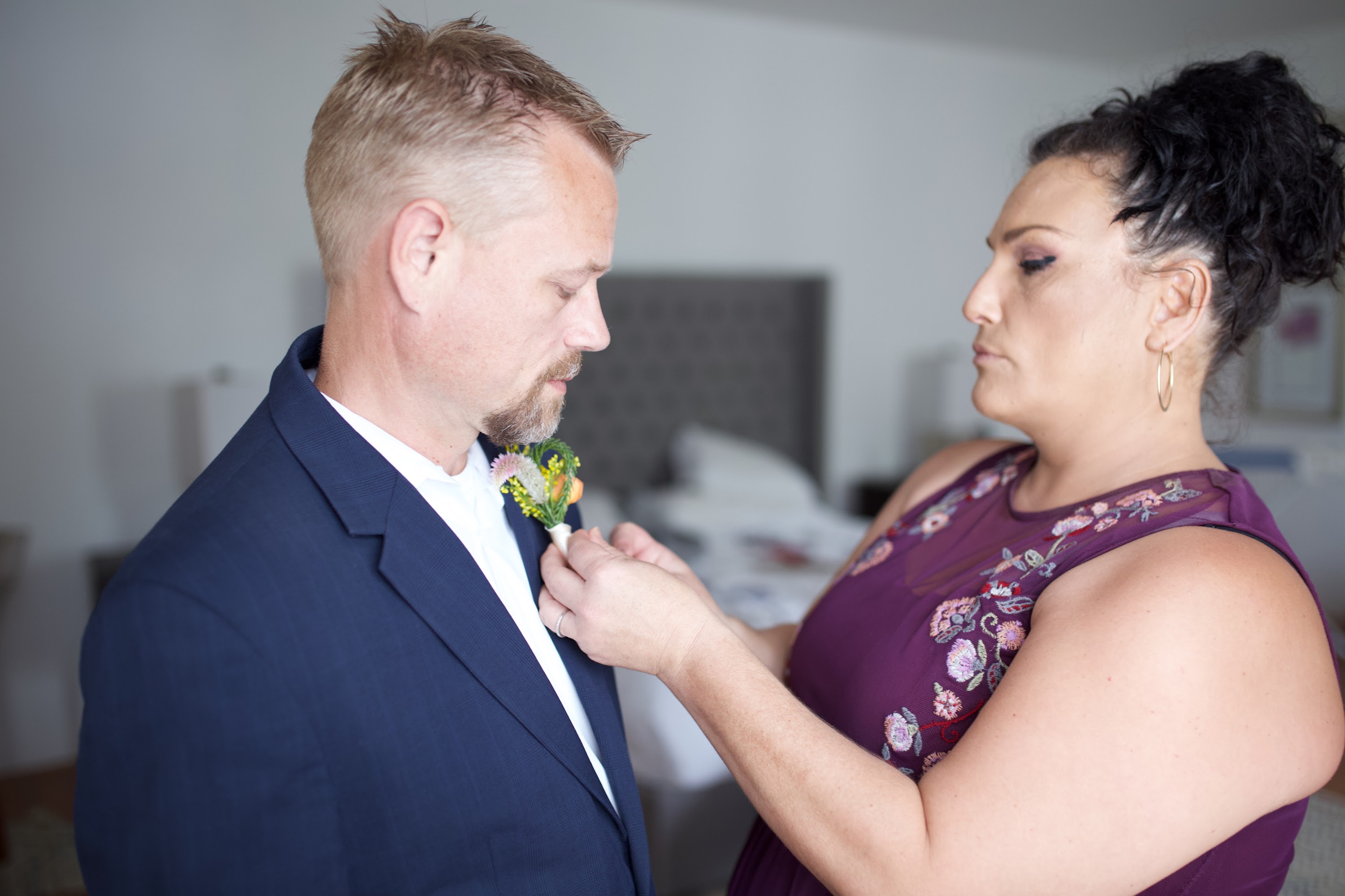 Woman pinning boutonniere on man's suit