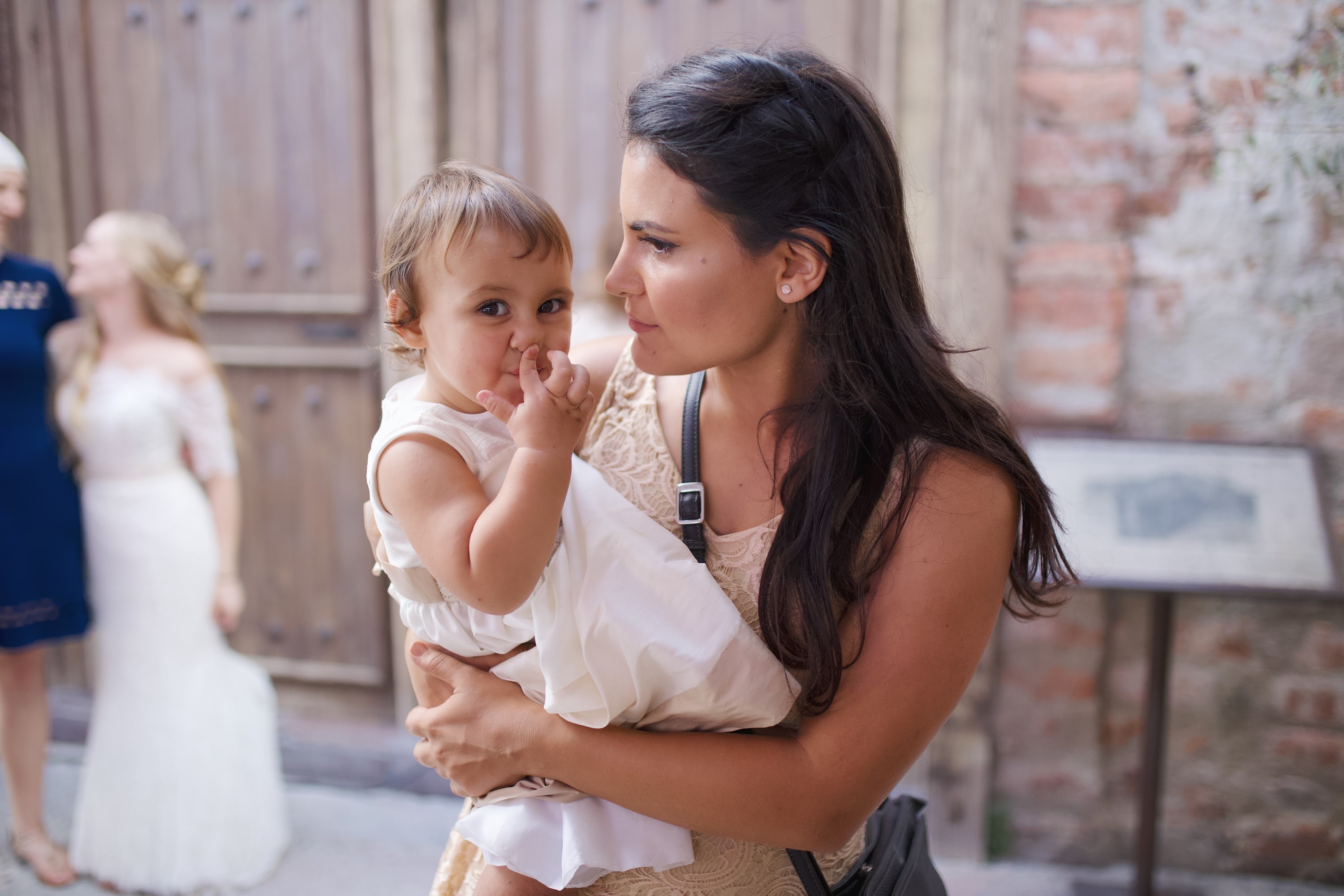 Mother Holding Baby Girl Outdoors Near Wooden Door