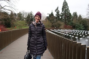 Woman on Bridge Over Pond with Floating Star-shaped Lights