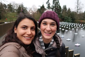 Two Women Smiling by a Pond with Paper Boats