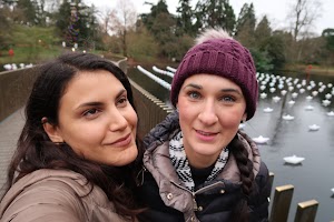 Two Women Taking a Selfie by a Pond with Paper Boats