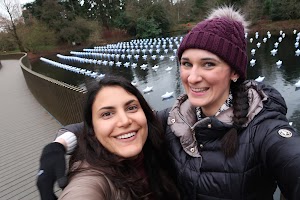 Two Women Smiling on a Bridge with Floating Paper Boats