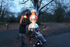 Woman and Child Near Illuminated Snowman Sculpture in Park