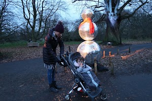 Woman and Child Viewing a Disco Ball Snowman in Park at Dusk