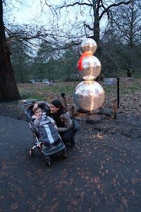Woman and Baby with Glittering Snowman Sculpture in Park