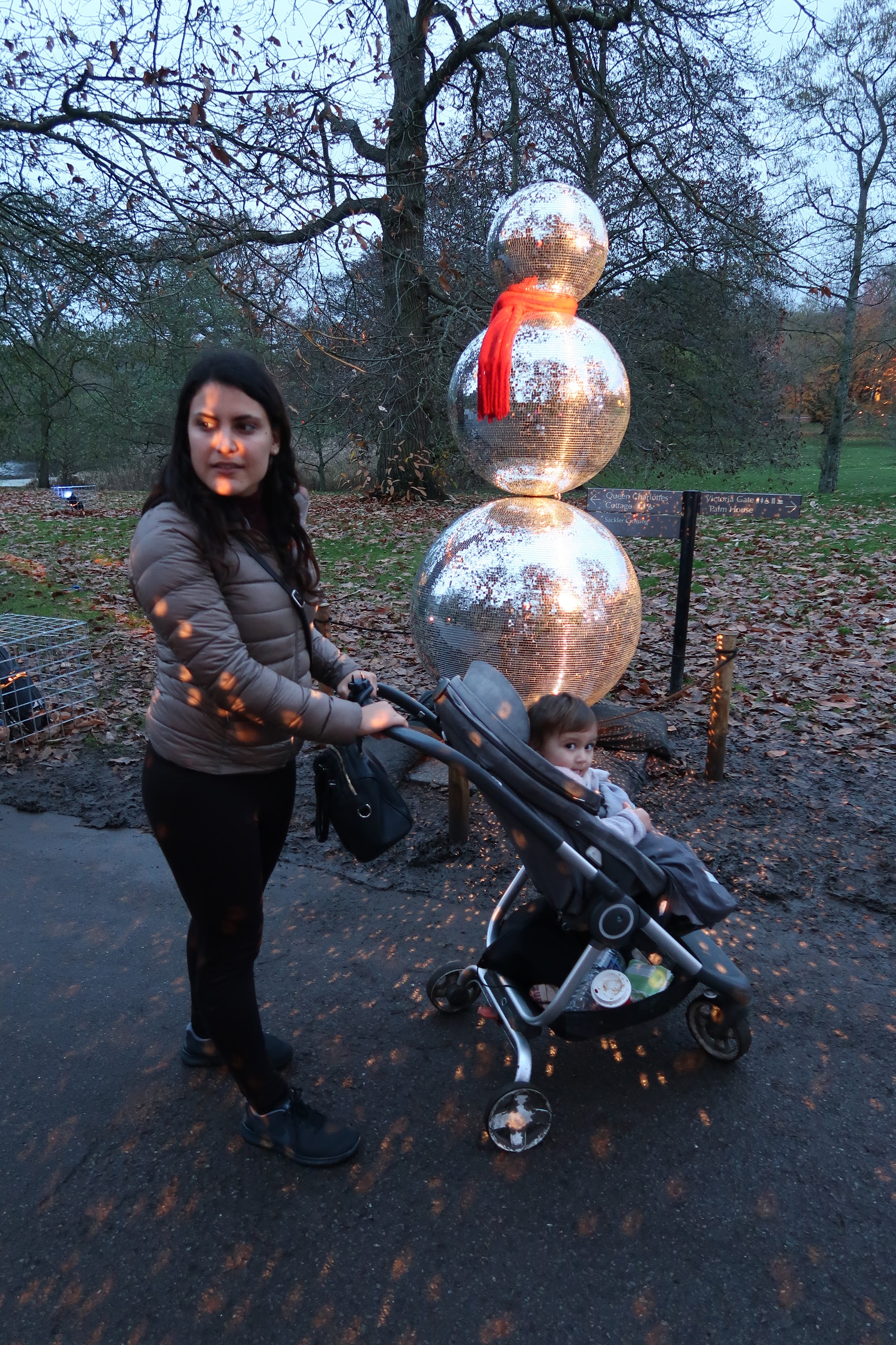 Woman and Child with Reflective Snowman Sculpture in Park