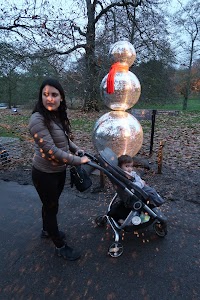 Woman and Child with Reflective Snowman Sculpture in Park