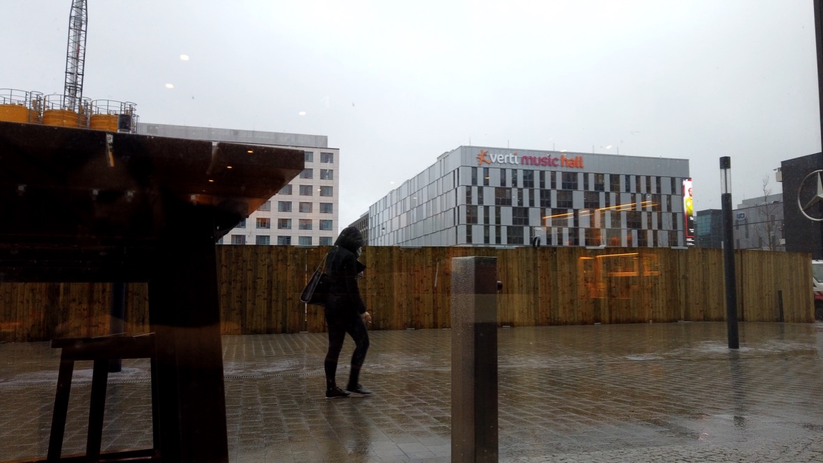 Person Walking Outside Vertu Music Hall on Rainy Day