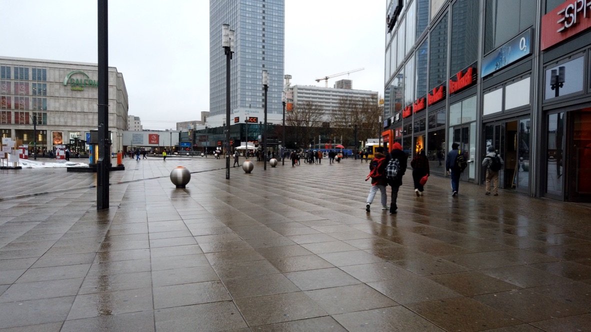 Rainy Urban Plaza with Pedestrians and Modern Buildings