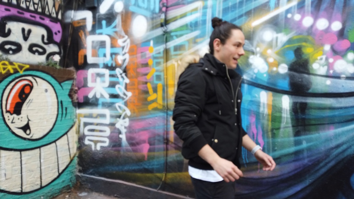Man Walking Past Colorful Graffiti Wall