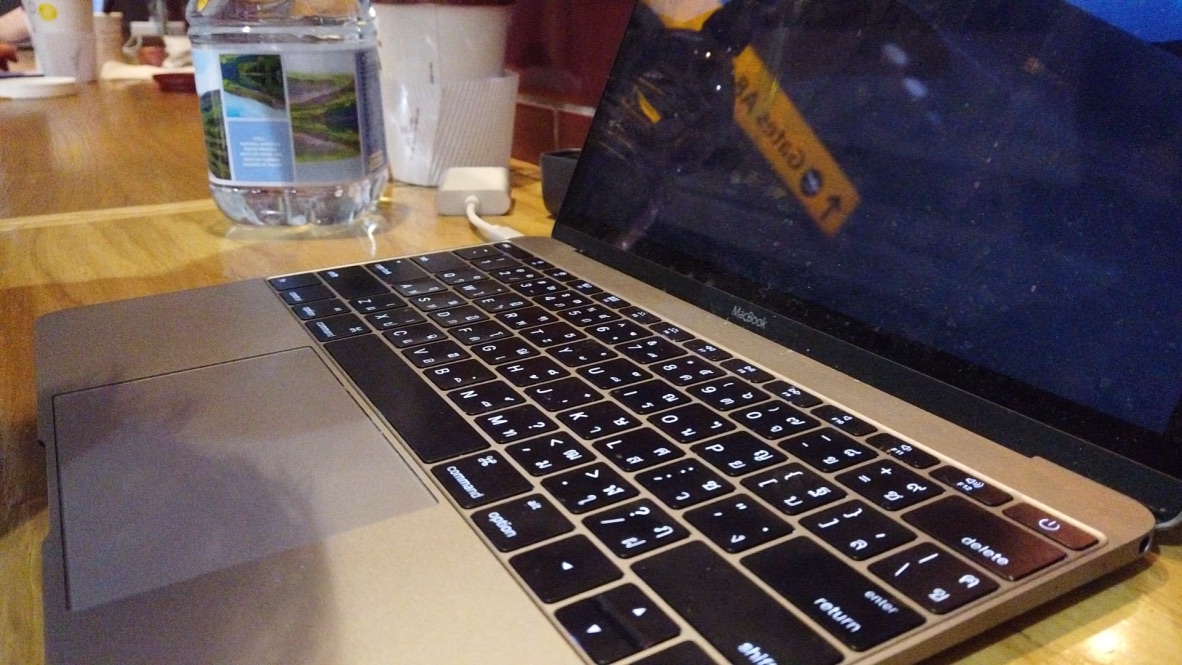 Gold MacBook on Wooden Table with Water Bottle