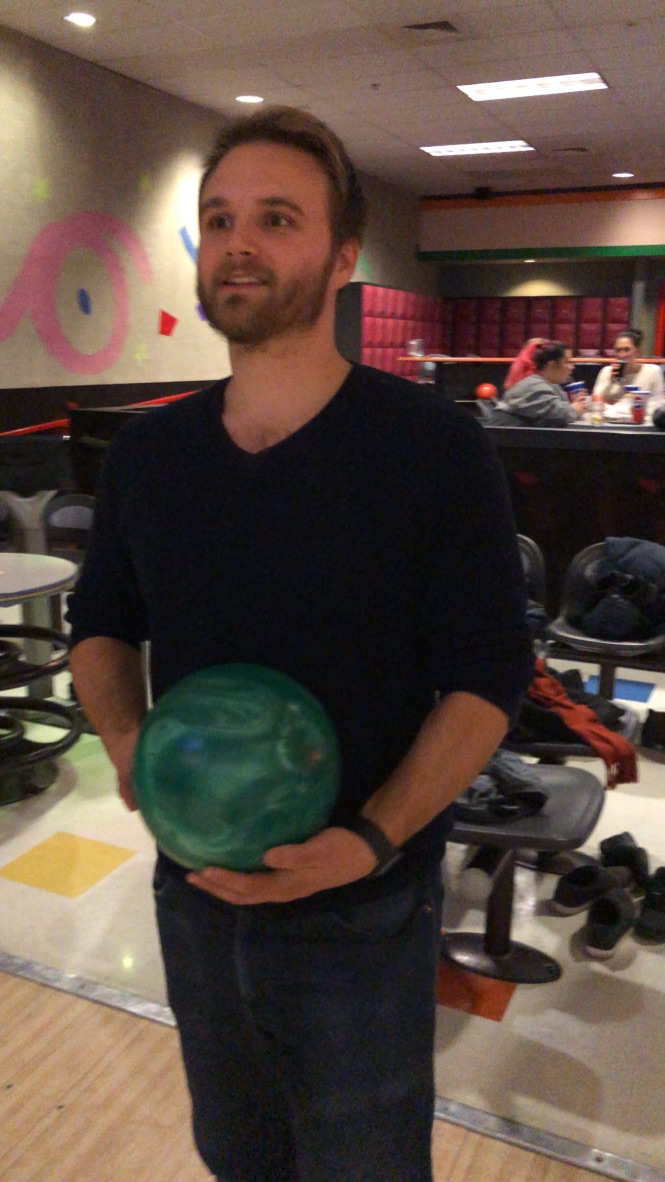 Man Holding Green Bowling Ball at Alley