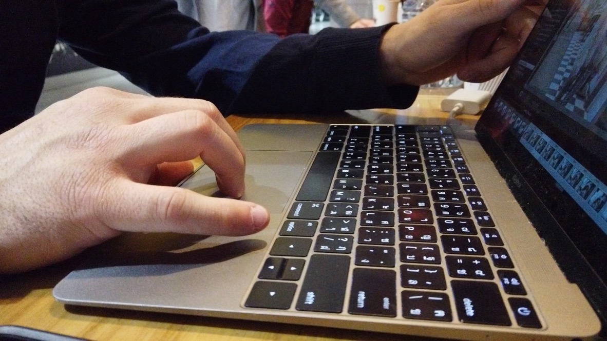 Person Using MacBook Laptop on Wooden Table