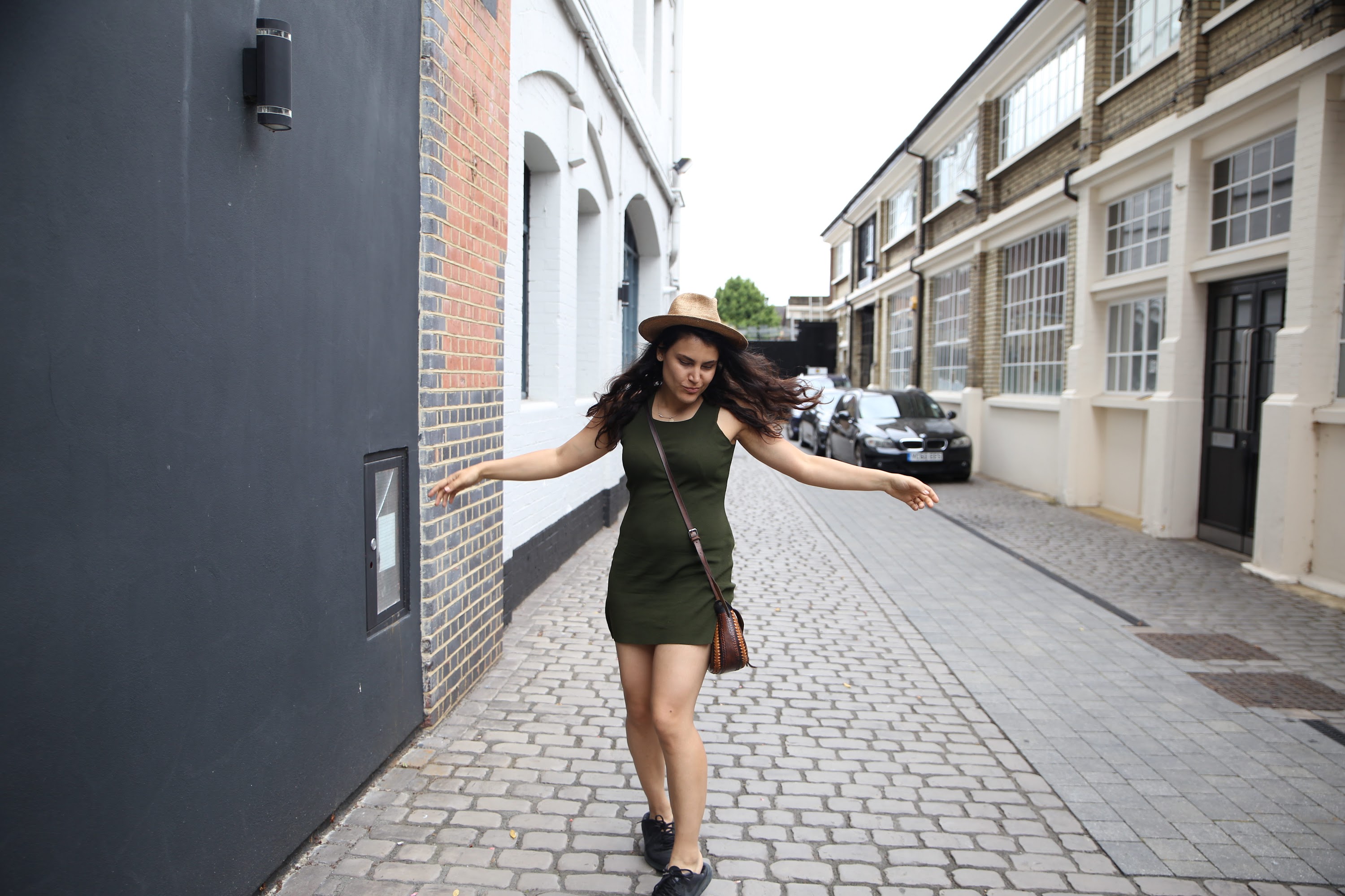 Woman in Green Dress Dancing on Cobblestone Alley