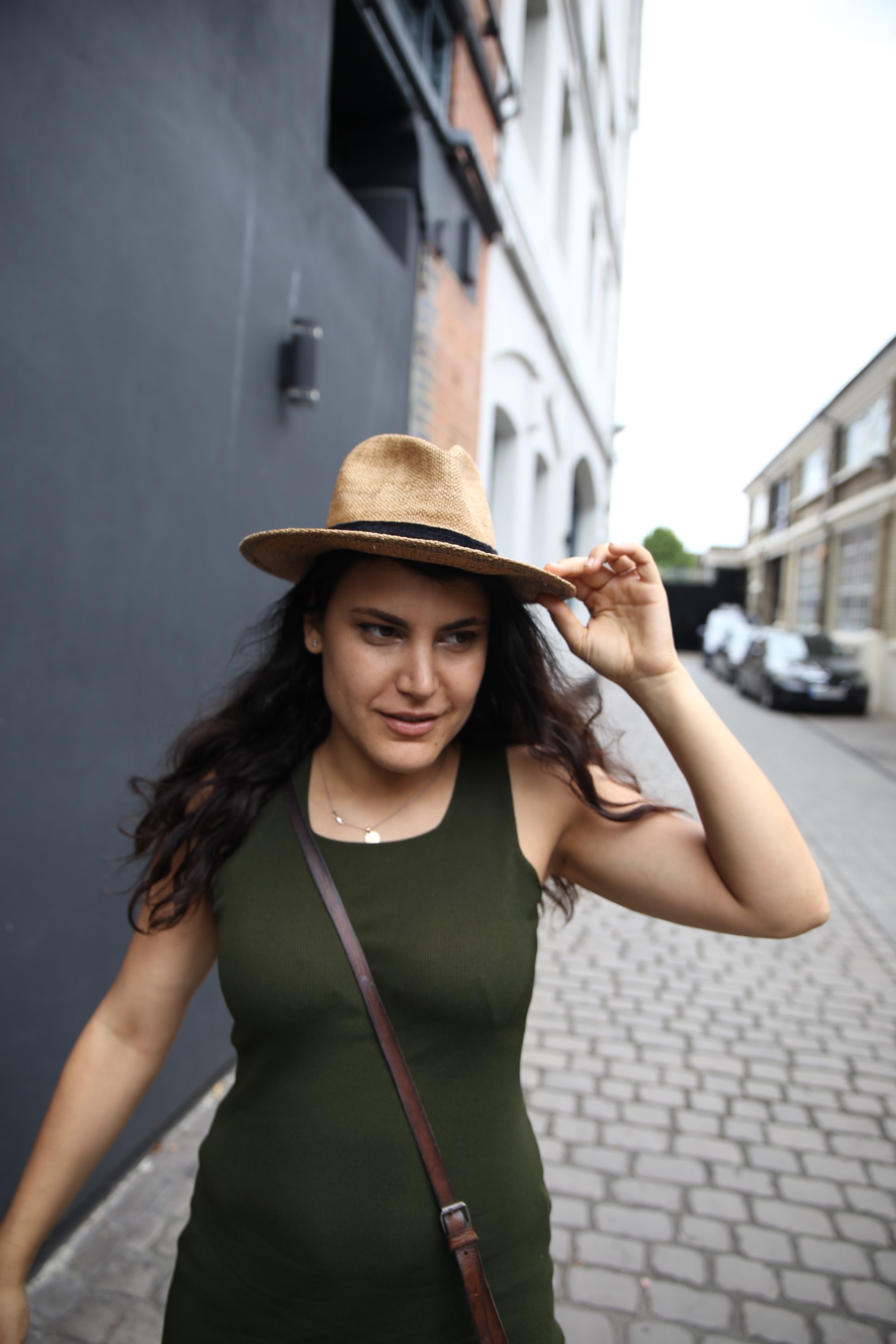 Woman Adjusting Straw Hat on Cobblestone Street