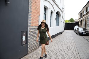 Woman Walking Down Cobblestone Alley in Green Dress and Hat