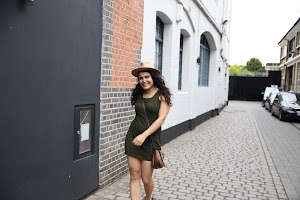 Woman in Green Dress and Hat Walking on Cobblestone Street