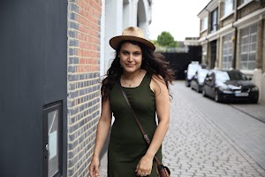 Woman in Green Dress and Straw Hat on Cobblestone Street