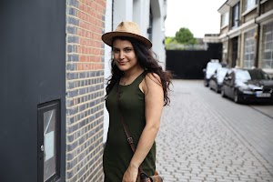 Woman in Hat and Green Dress Standing on Cobblestone Street