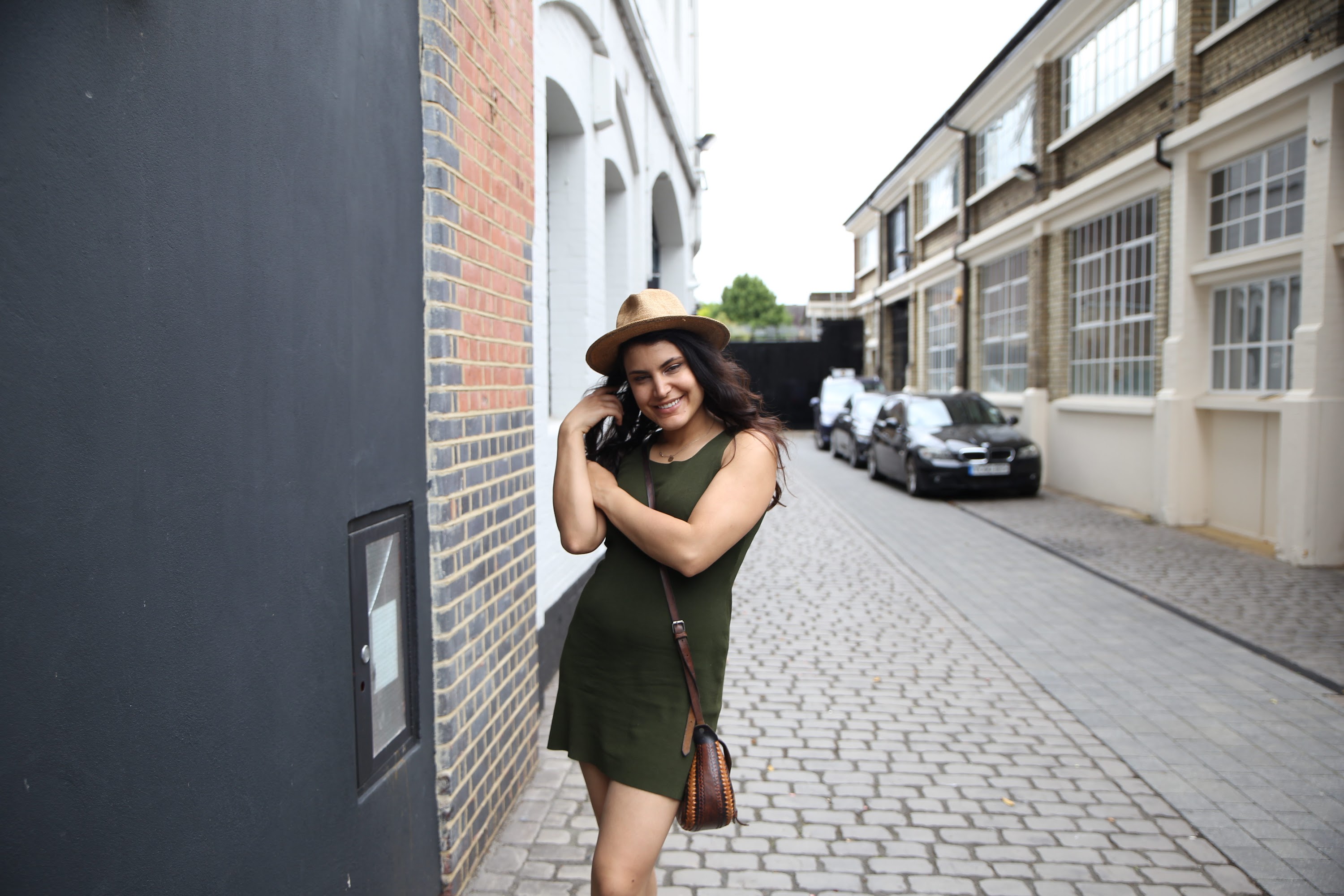 Woman in Green Dress and Hat on Cobblestone Street