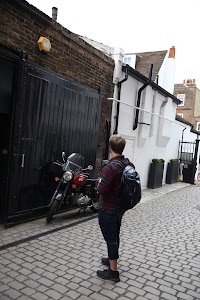 Man Standing in Cobblestone Alley with Red Motorcycle