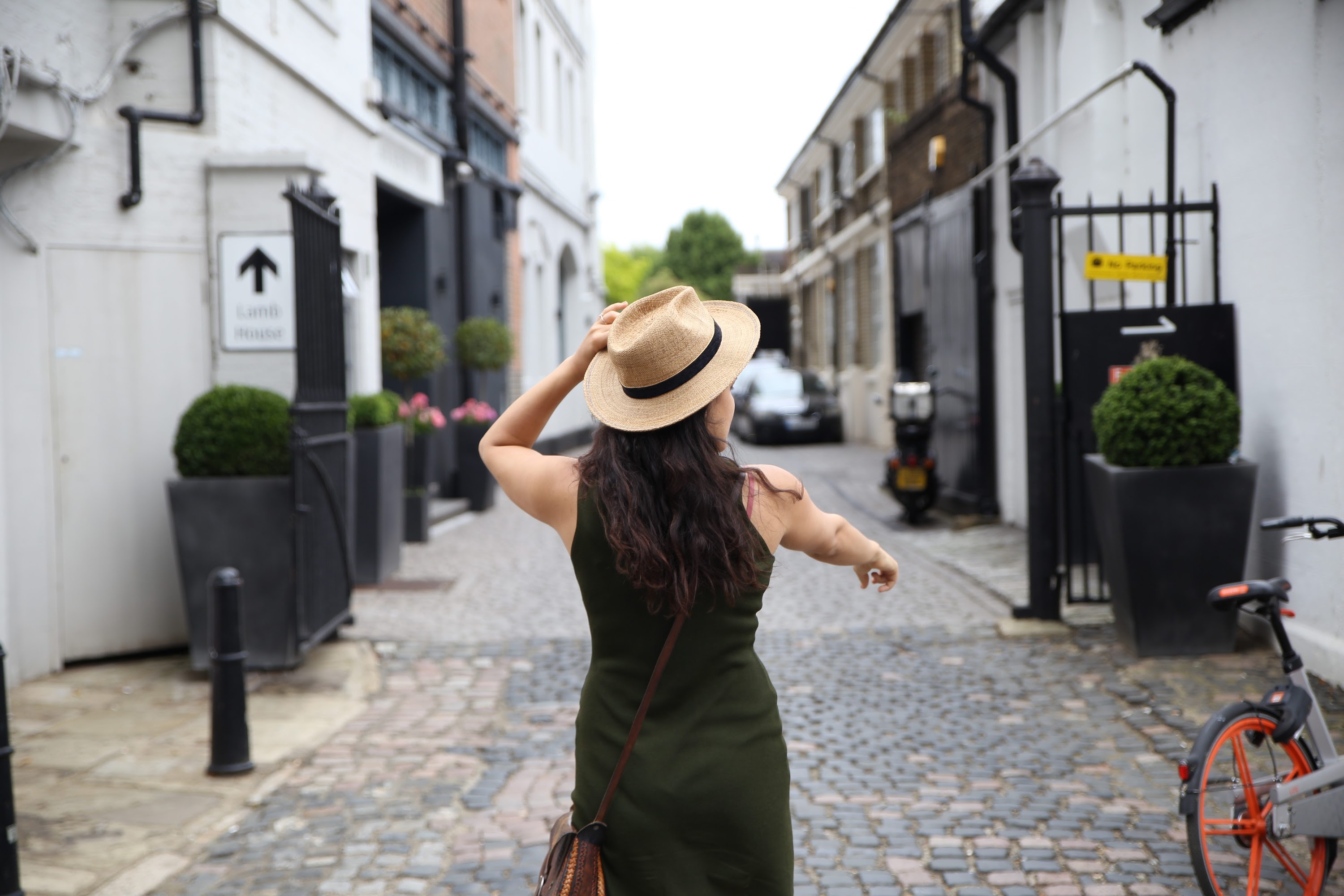 Woman in Green Dress Walking Down Cobblestone Alley