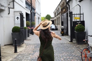 Woman in Green Dress Walking Down Cobblestone Alley