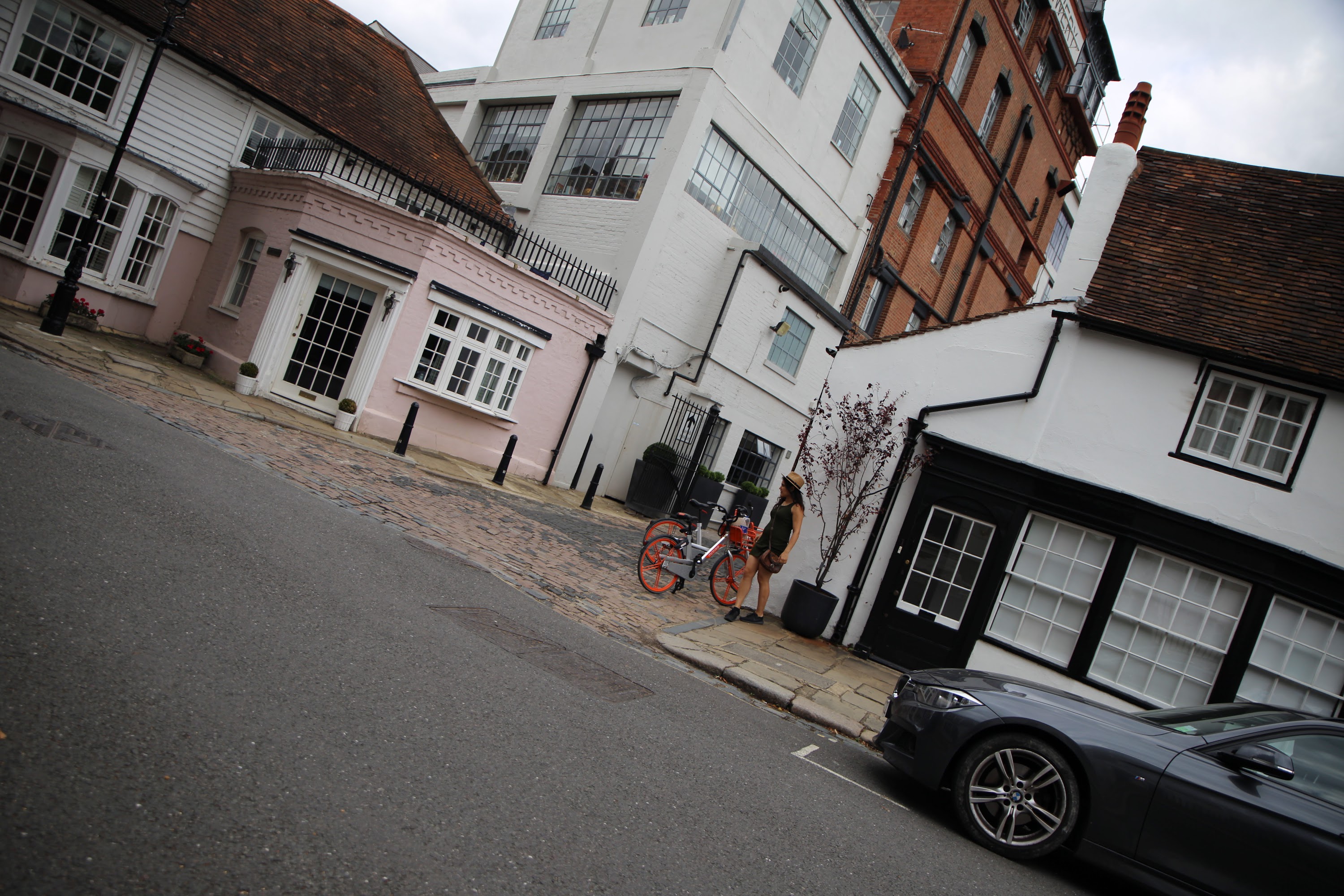 Person with Orange Bicycle on Cobblestone Street
