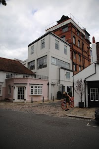 Person with Red Bicycle on Cobblestone Street Near Studios Building