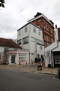 Person Crouching Near Red Bicycle in Front of White and Brick Studios Building