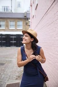 Smiling Woman in Straw Hat Against Pink Brick Wall