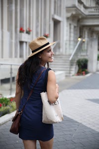 Woman in Blue Dress and Straw Hat Walking on City Street