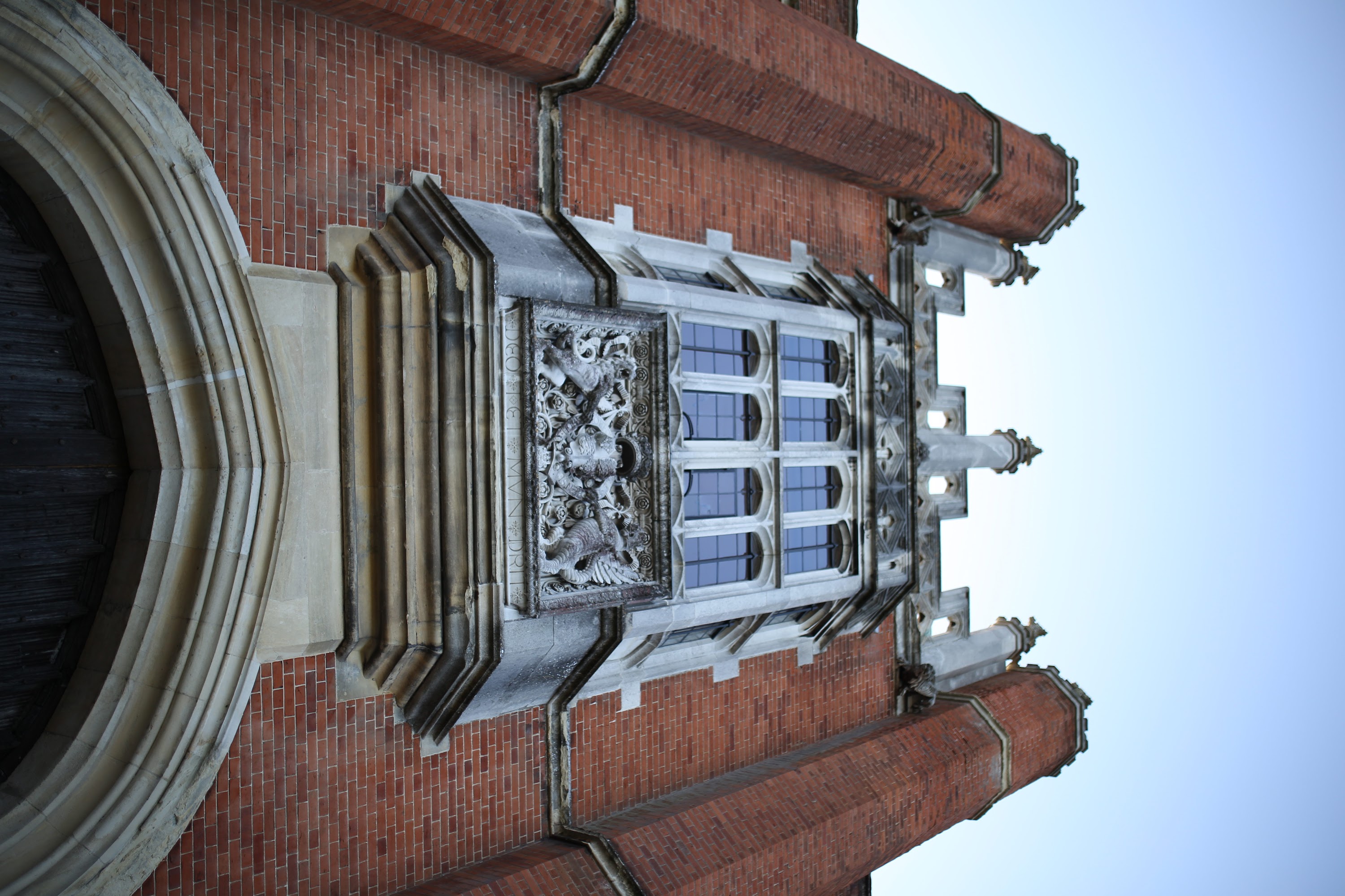 Gothic-style brick building with ornate stone window and heraldic carving