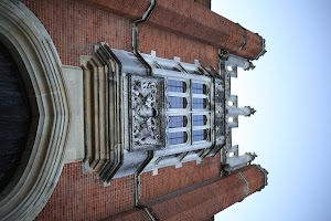 Gothic-style brick building with ornate stone window and heraldic carving
