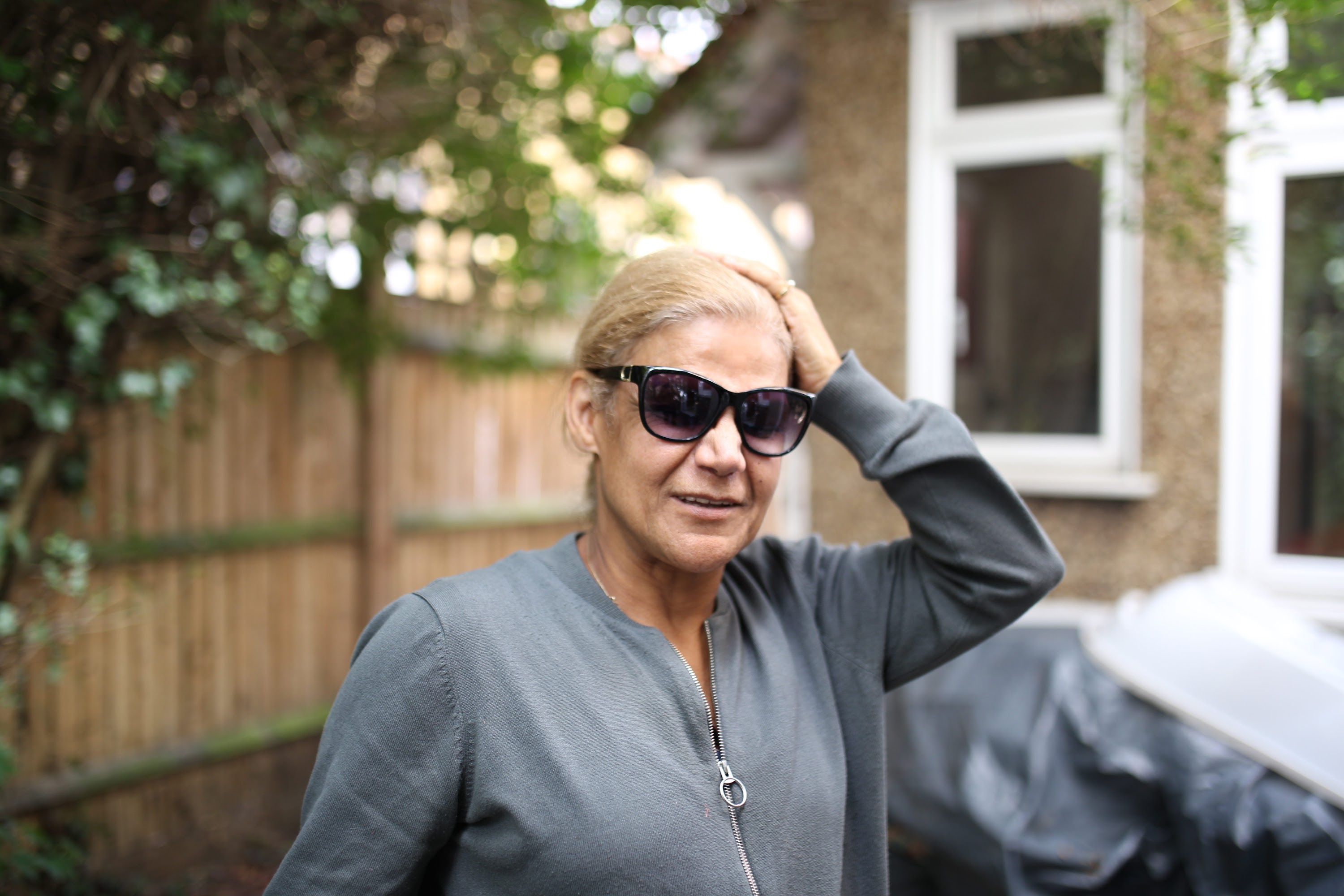 Woman in Sunglasses Adjusting Hair in Garden