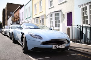 Light Blue Aston Martin DB11 Parked on a Colorful Street