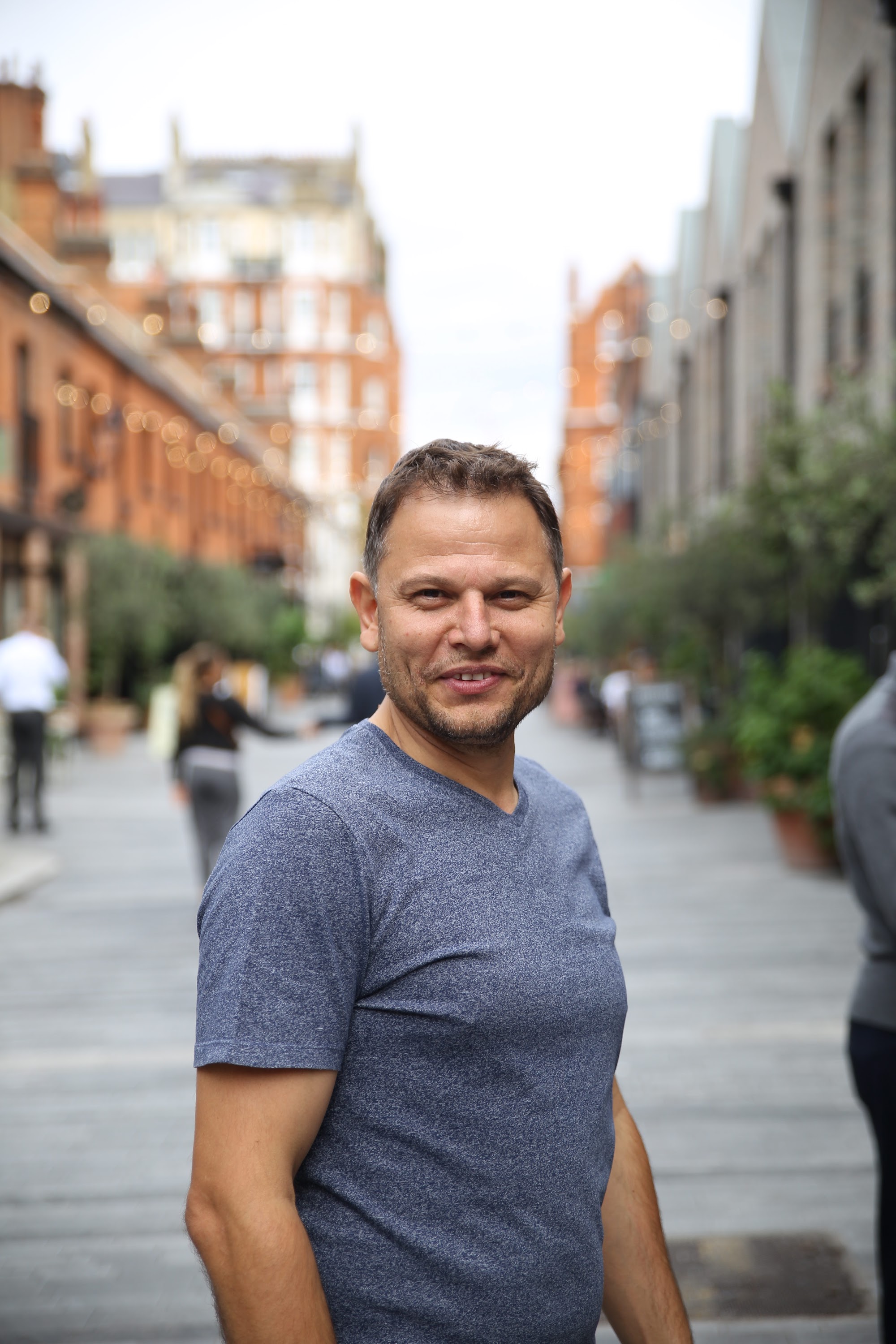 Smiling Man in Blue T-Shirt on Urban Street