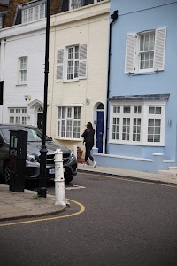 Woman Walking Past Colorful Townhouses on a Quiet Street